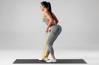 Atletik kız direniş bandıyla egzersiz yapıyor. Spor salonundaki kadın.