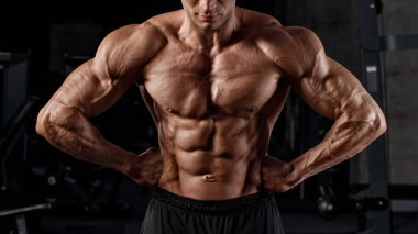 Spor salonunda kaslarını gösteren kaslı bir adam. Güçlü erkek çıplak gövde kasları