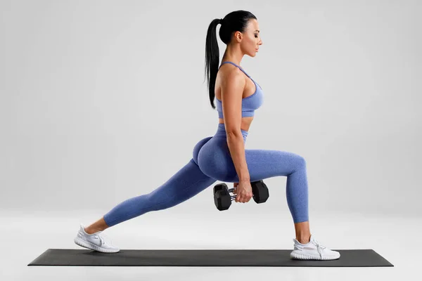 フィットネス女性は足の筋肉のトレーニングのための肺の演習を行う アクティブ女の子を行う前に1足のステップ肺運動 上の灰色の背景 — ストック写真