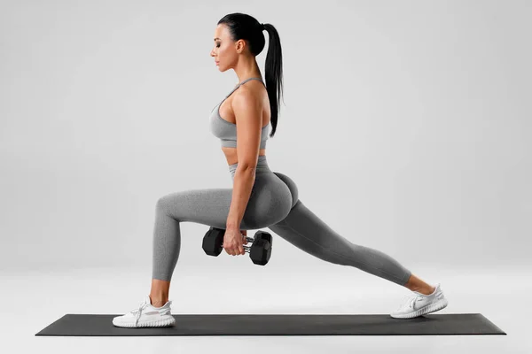 Active girl doing lunges exercises for leg muscle workout training. Fitness woman doing front forward one leg step lunge exercise