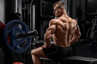 Spor salonunda kaslı bir adam sırt kaslarını gösteriyor. Güçlü erkek dikiz aynası