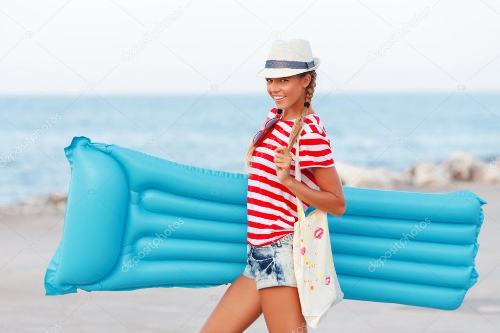 Woman with blue mattress at the beach