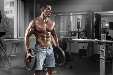 Kaslı adam ile halter, spor salonunda egzersiz karın şeklinde. Güçlü erkek çıplak gövde abs