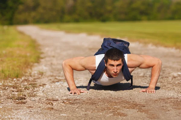 Hombre de fitness ejercitando flexiones, al aire libre. Entrenamiento muscular masculino fuera — Foto de Stock