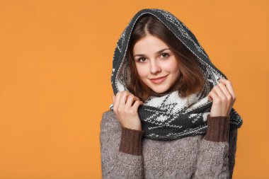 Örme giyen Noel kız giyim eşarp. Turuncu arka plan üzerinde izole genç güzel gülümseyen kız, kış kavramı,