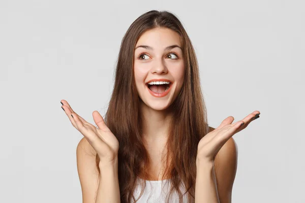 Surpreendido mulher bonita feliz olhando para os lados em emoção. Isolado em cinza — Fotografia de Stock