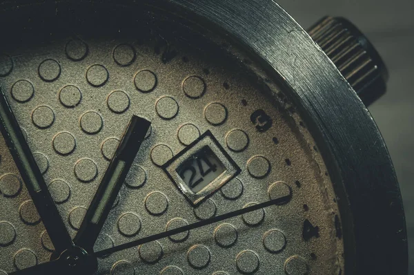 The dial of an old wristwatch with a scratched glass in the macro.