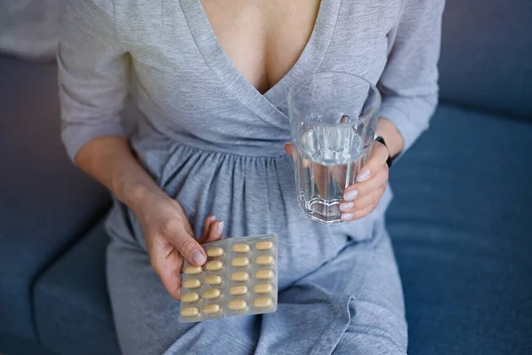 Junge Schwangere Frau Nimmt Medikamente Und Trinkt Wasser lizenzfreie Stockfotos