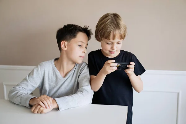 Netter Junge Schaut Seinen Bruder Beim Smartphone Spielen lizenzfreie Stockbilder