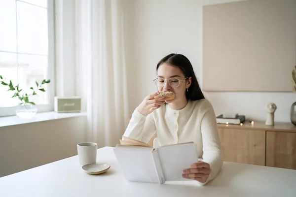 Hübsches Teenager Mädchen Liest Buch Und Trinkt Kaffee Hause lizenzfreie Stockbilder