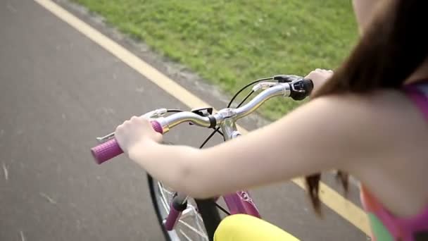 Niña en bicicleta en el parque en una bicicleta rosa. Movimiento lento — Vídeos de Stock