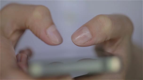 Junge Frau tippt mit den Fingern auf ihrem Smartphone. — Stockvideo