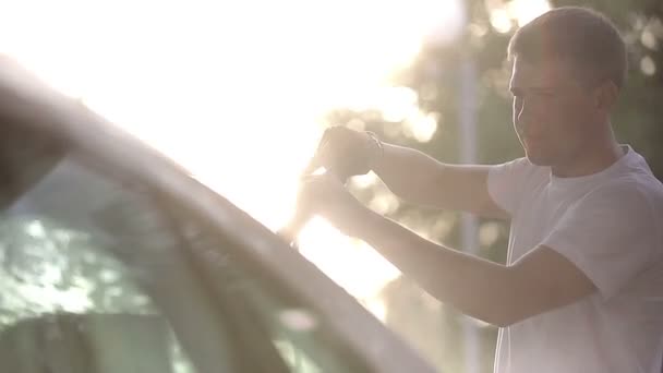 Man in a white t-shirt white car washes. — Stock Video