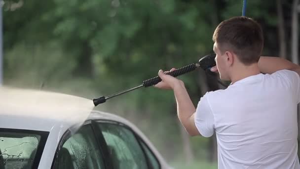 Чоловік у білій футболці миє білий автомобіль . — стокове відео