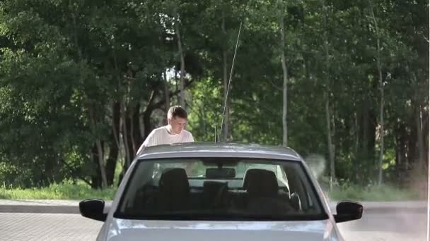 Mann im weißen T-Shirt wäscht weißes Auto. — Stockvideo