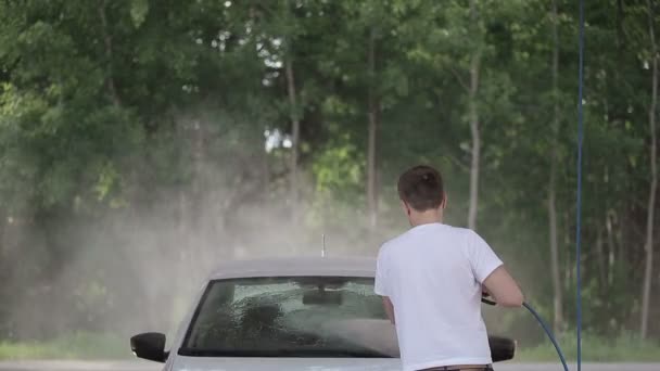 Man in een wit t-shirt wit autowasstraten. — Stockvideo