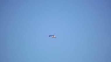 Küçük helikopter mavi gökyüzüne karşı uçar ve ağaçlara uçar