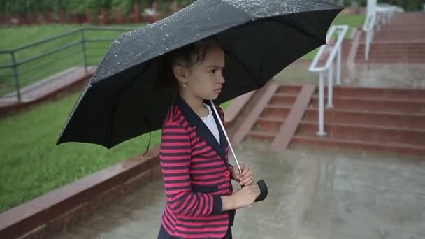 Ensamma barnflickan i regnet med ett paraply. Slow motion. — Stockvideo