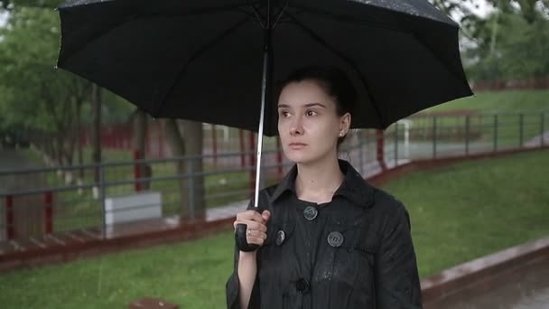 Niña solitaria bajo la lluvia con un paraguas. Movimiento lento . — Vídeo de stock