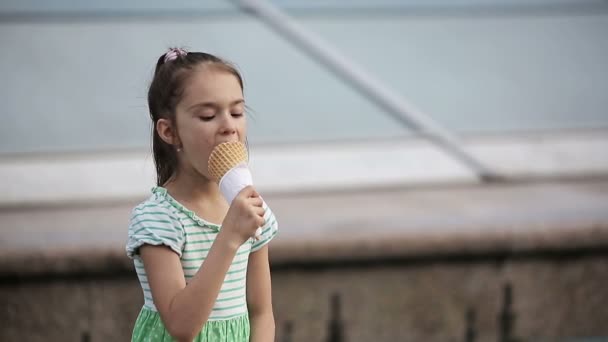 Gyönyörű gyermek kislány eszik fagylaltot az utcán. — Stock videók