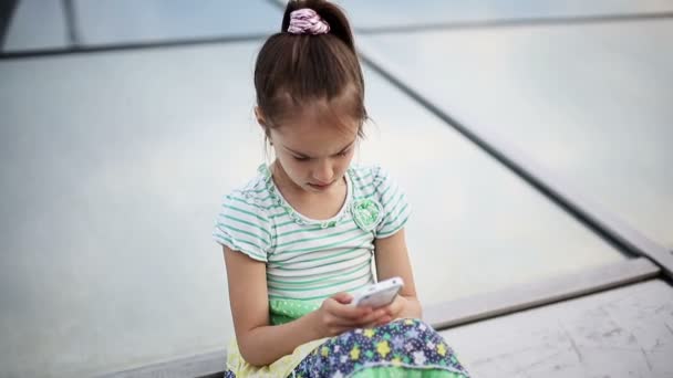 Beautiful child little girl kid enjoys smartphone. — Stock Video