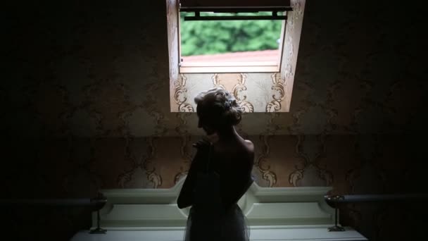 Κομψό νύφη καυκάσιος φοράει ένα νυφικό που στέκεται στο παράθυρο — Αρχείο Βίντεο