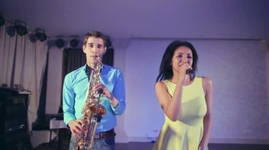 Caz kadın şarkıcı ve ince saksafon çalar. Yaratıcı ikilisi. Stüdyo ışıkları. Ağır çekim