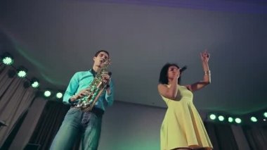 Caz kadın şarkıcı ve ince saksafon çalar. Yaratıcı ikilisi. Stüdyo ışıkları. Ağır çekim