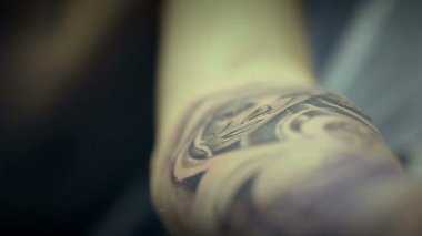 Dövme sanatçısı çalışma. Adam kolunu kadının yüzünde çizer. Dövme salonu