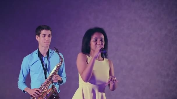 Énekes jazz nő és vékony szaxofon-lejátszó. A kreatív duó. Stúdió világítását. Lassú mozgás — Stock videók