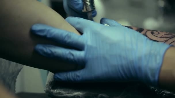 Tattoo artist working. Man draws on his arm woman's face. Tattoo salon — Stock Video