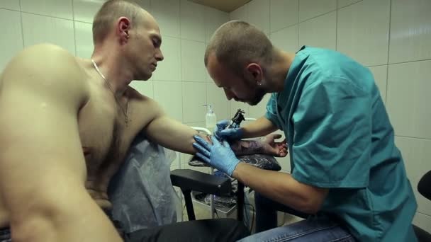 Tetovací umělec pracuje. Člověk čerpá z jeho ruku ženská tvář. Tattoo salón — Stock video