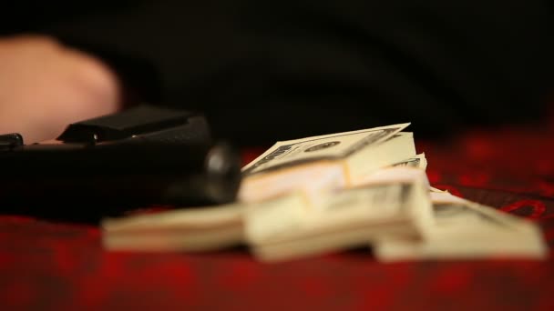 Pistola e tre pacchetti di dollari sul tavolo con un panno rosso — Video Stock