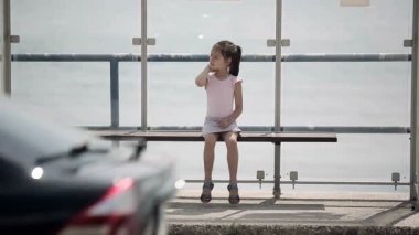 Bir otobüs otobüs durağında bekleyen çocuk etrafına bakıyor ve özlüyor.