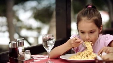 Çocuk Adriyatik Denizi kıyısında bulunan restoranda spagetti makarna yiyor.