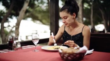 Kadın Adriyatik Denizi kıyısında bulunan restoranda spagetti makarna yiyor.