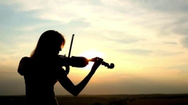 Siluet kız kemancı günbatımı gökyüzü arka plan keman çalıyor. Renk v.1