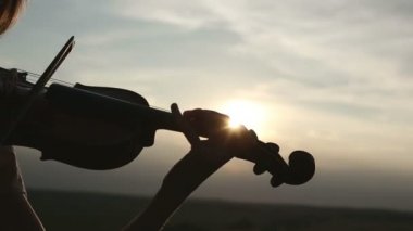 Siluet kız kemancı günbatımı gökyüzü arka plan keman çalıyor. Düşük ihtimal. Renk v.2