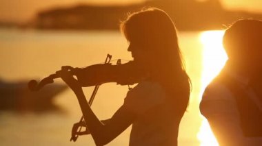 Keman düet erkek ve kadın keman doğa günbatımı gölde oynamak