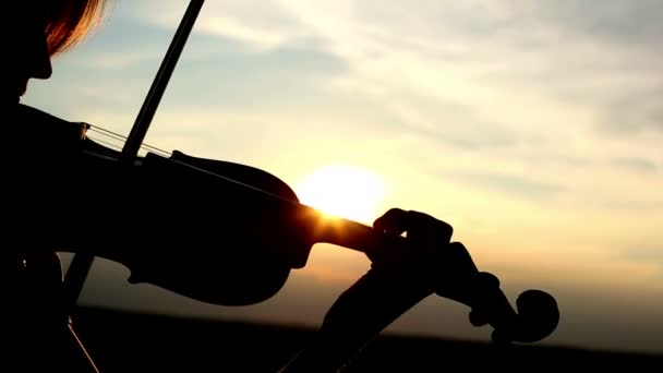 Violinista chica silueta tocando el violín al atardecer fondo cielo. Color v.1 — Vídeo de stock