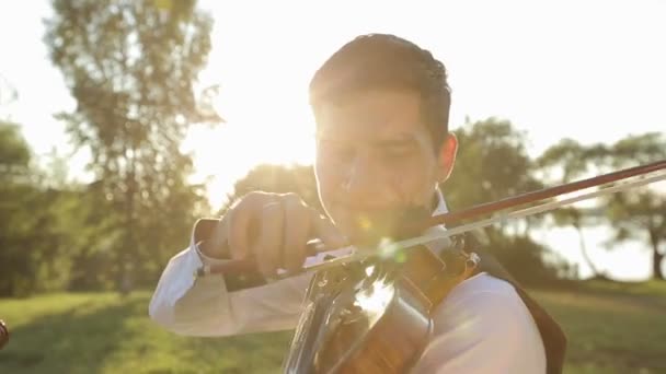 Viool duet man en vrouw speelt viool op aard bij de zonsondergang op het meer — Stockvideo