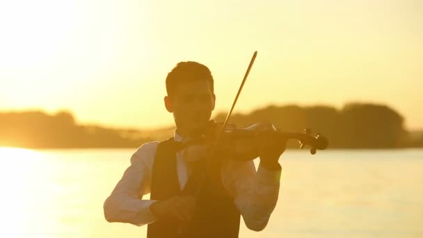 Скрипаль грає на скрипці на природі на заході сонця — стокове відео