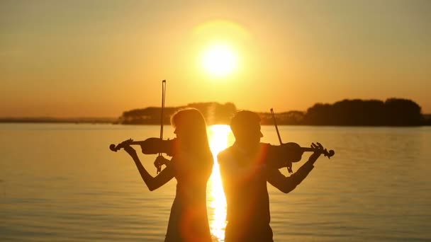 Geigenduett Mann und Frau spielen Geige in der Natur beim Sonnenuntergang am See — Stockvideo