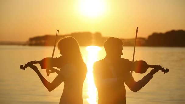 Violin duet man och kvinna spela fiol på natur på solnedgången på sjön — Stockvideo