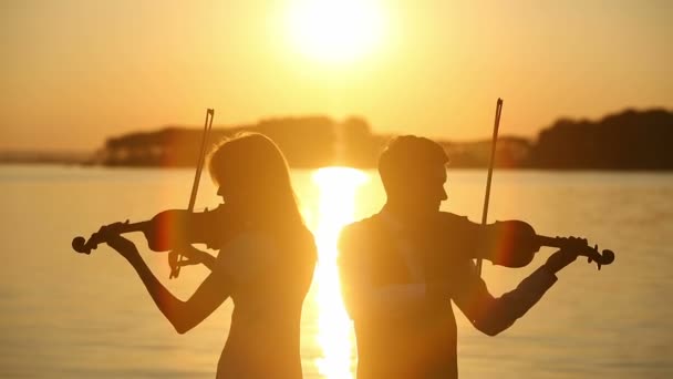 Geigenduett Mann und Frau spielen Geige in der Natur beim Sonnenuntergang am See