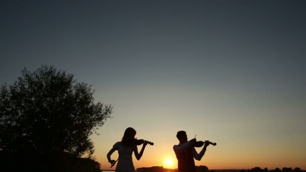 Geigenduett Mann und Frau spielen Geige in der Natur beim Sonnenuntergang am See
