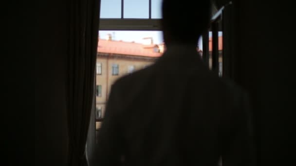 El hombre lleva una chaqueta de pie en el balcón del hotel — Vídeos de Stock