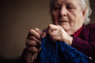 Yaşlı kadın evde oturur ve konfeksiyon dokuma kumaşlar