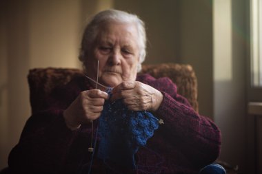 Yaşlı kadın evde oturur ve konfeksiyon dokuma kumaşlar