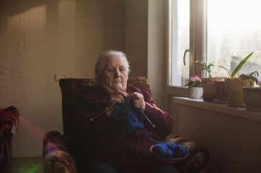 Yaşlı kadın evde oturur ve konfeksiyon dokuma kumaşlar